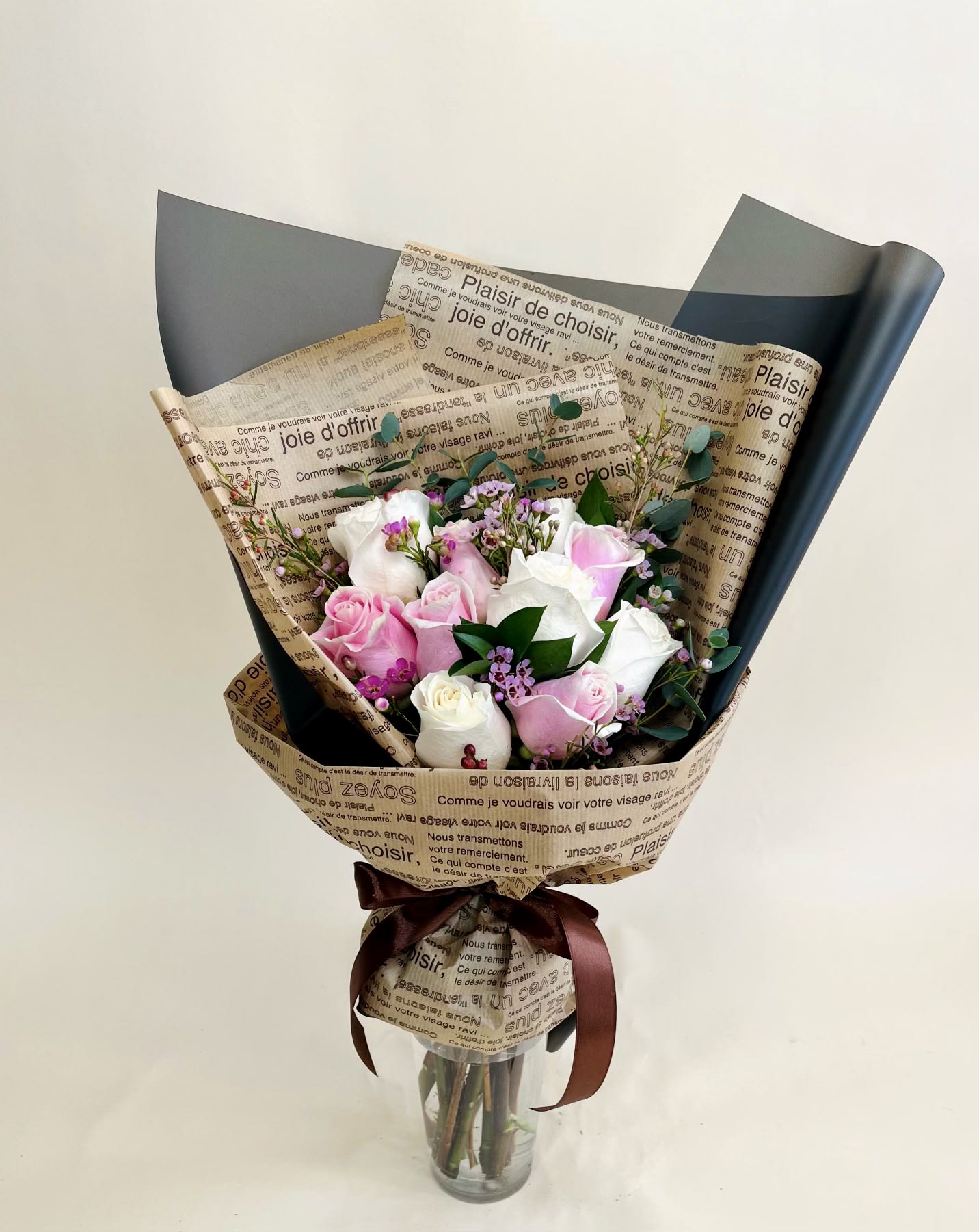 Daily News Hand Bouquet (Vase not included) - Light pink and white roses with accents of wax flowers - fashioned in a hand bouquet with bouquet wrapping paper. This bouquet does not include a vase.  