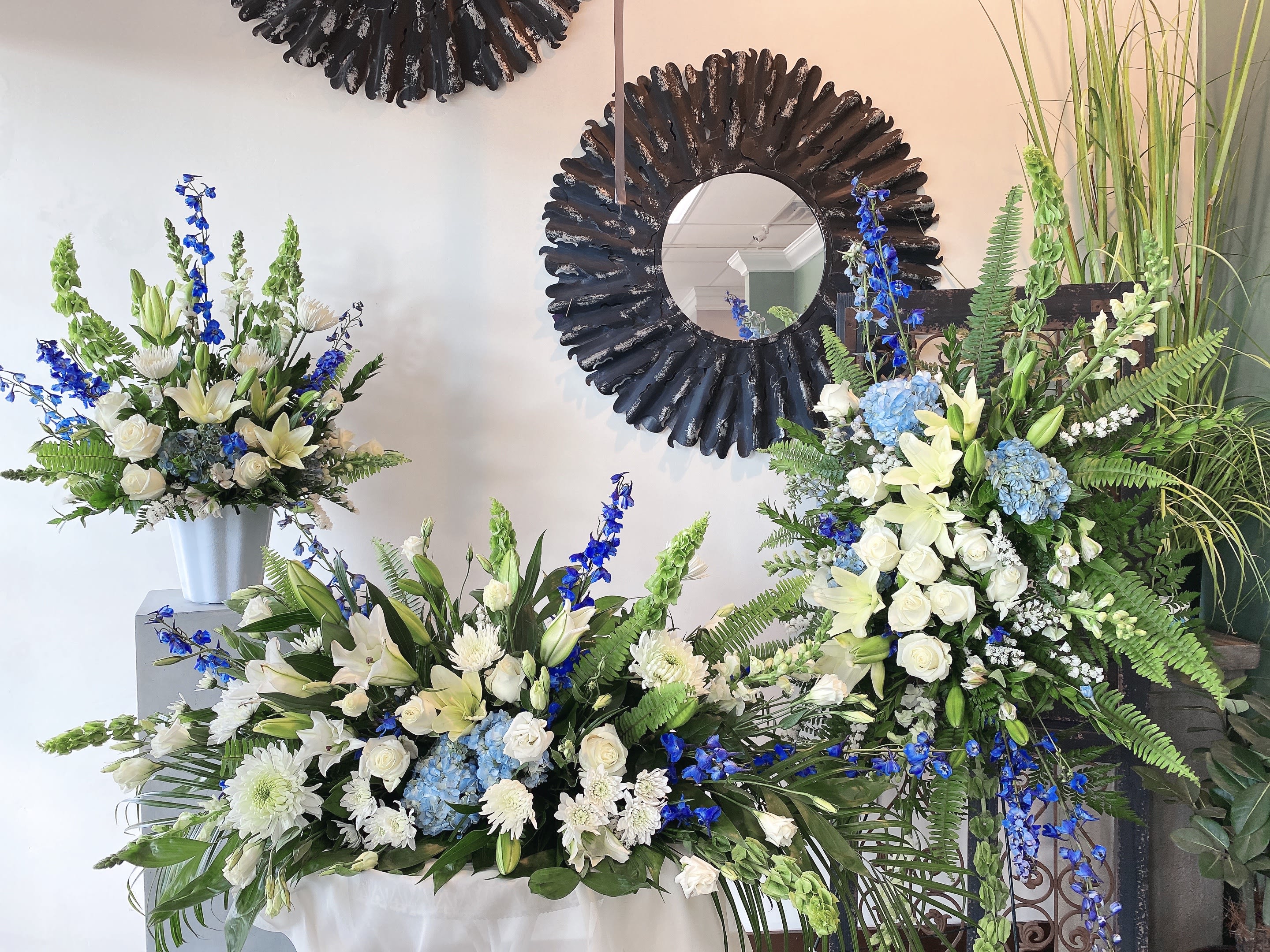 White and blue floral arrangements with lilies and roses in vases