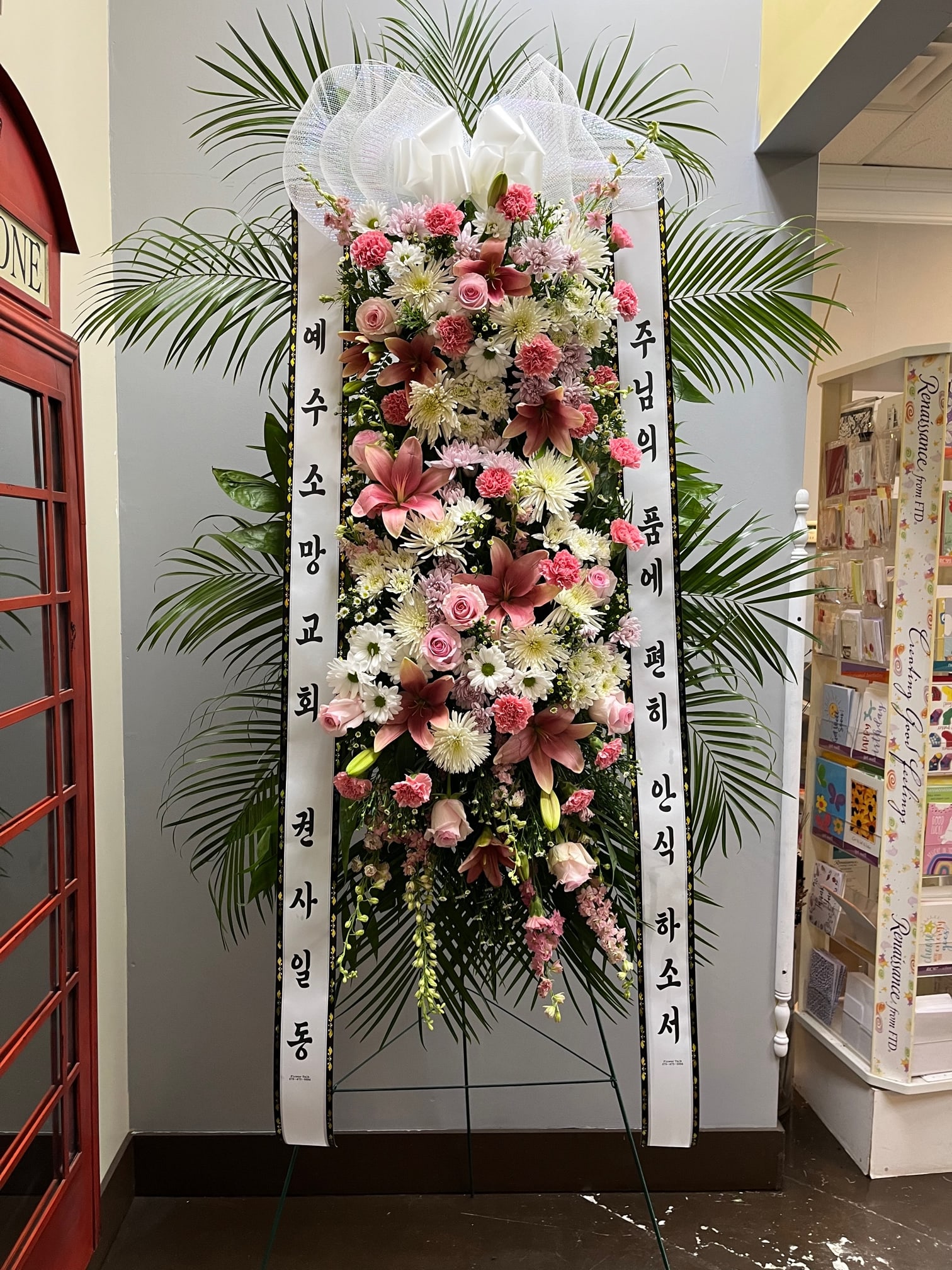 Tall standing floral wreath with pink and white flowers and Korean condolence ribbons