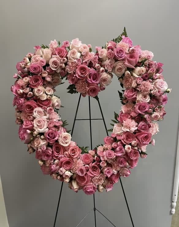 Heart-shaped floral wreath of pink and blush roses on a stand