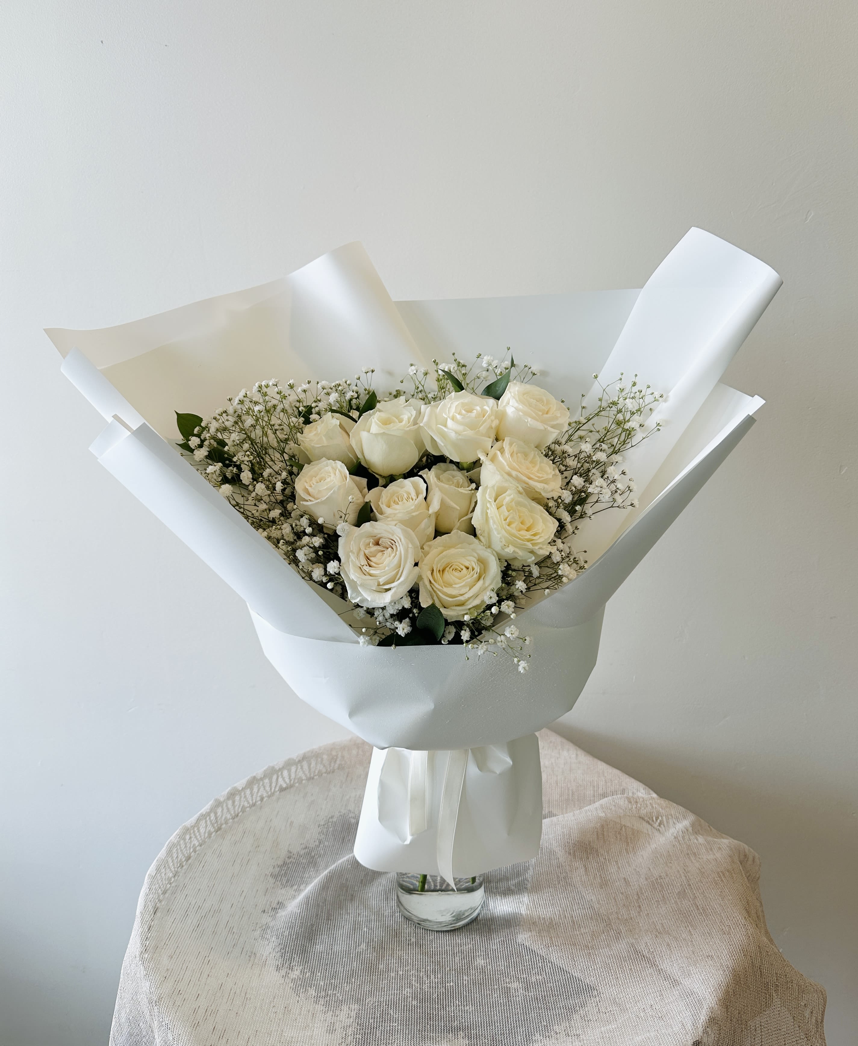 Bouquet of cream roses with baby's breath in white wrapping
