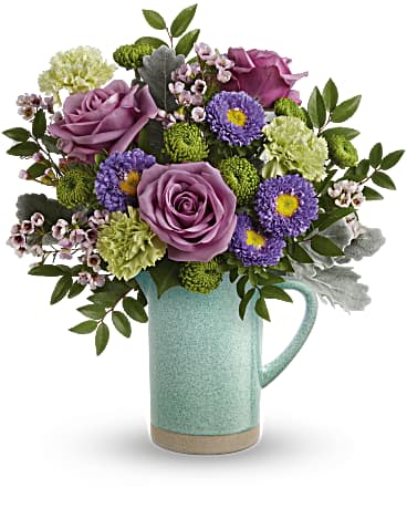 Purple roses and mixed blooms in a mint ceramic pitcher
