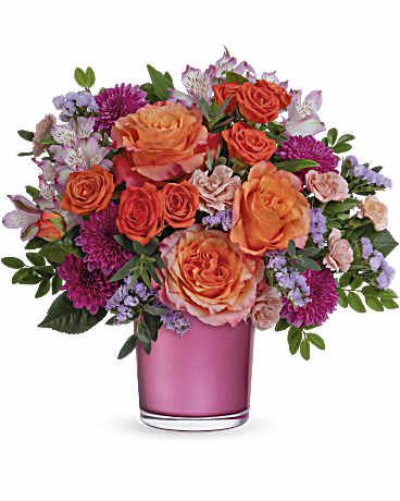 Orange and pink mixed flower bouquet in a pink glass vase