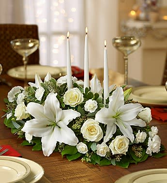 White floral centerpiece with lilies, roses, and tall taper candles