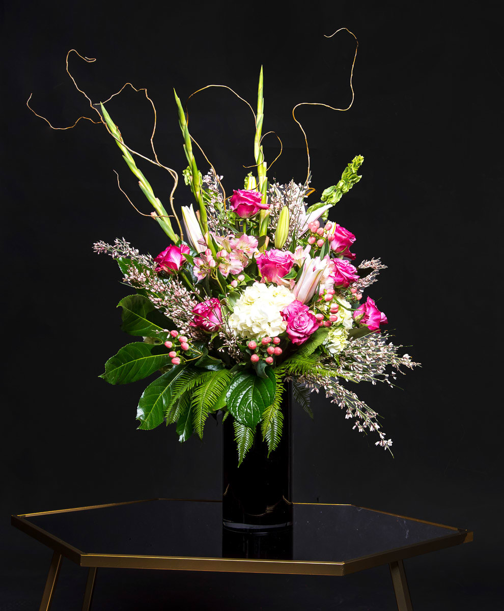 Pink and white floral arrangement in a black vase