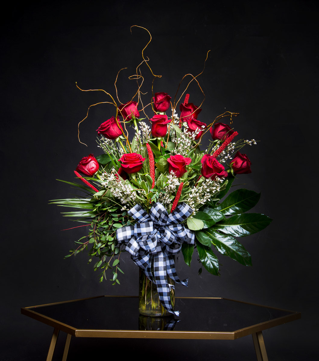 Red roses in a glass vase with a black-and-white ribbon