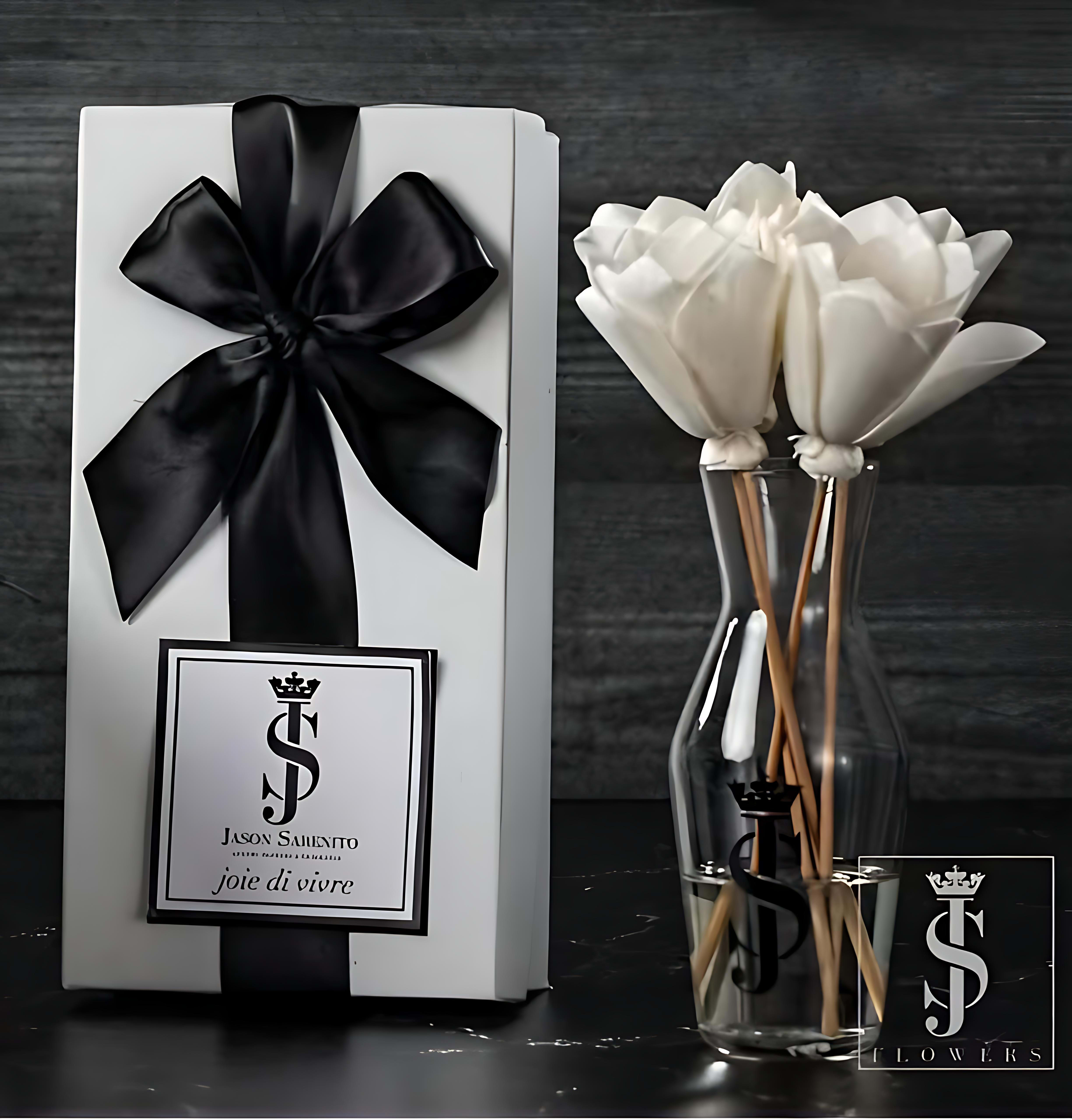 White flowers in a clear vase beside a white gift box with a black ribbon