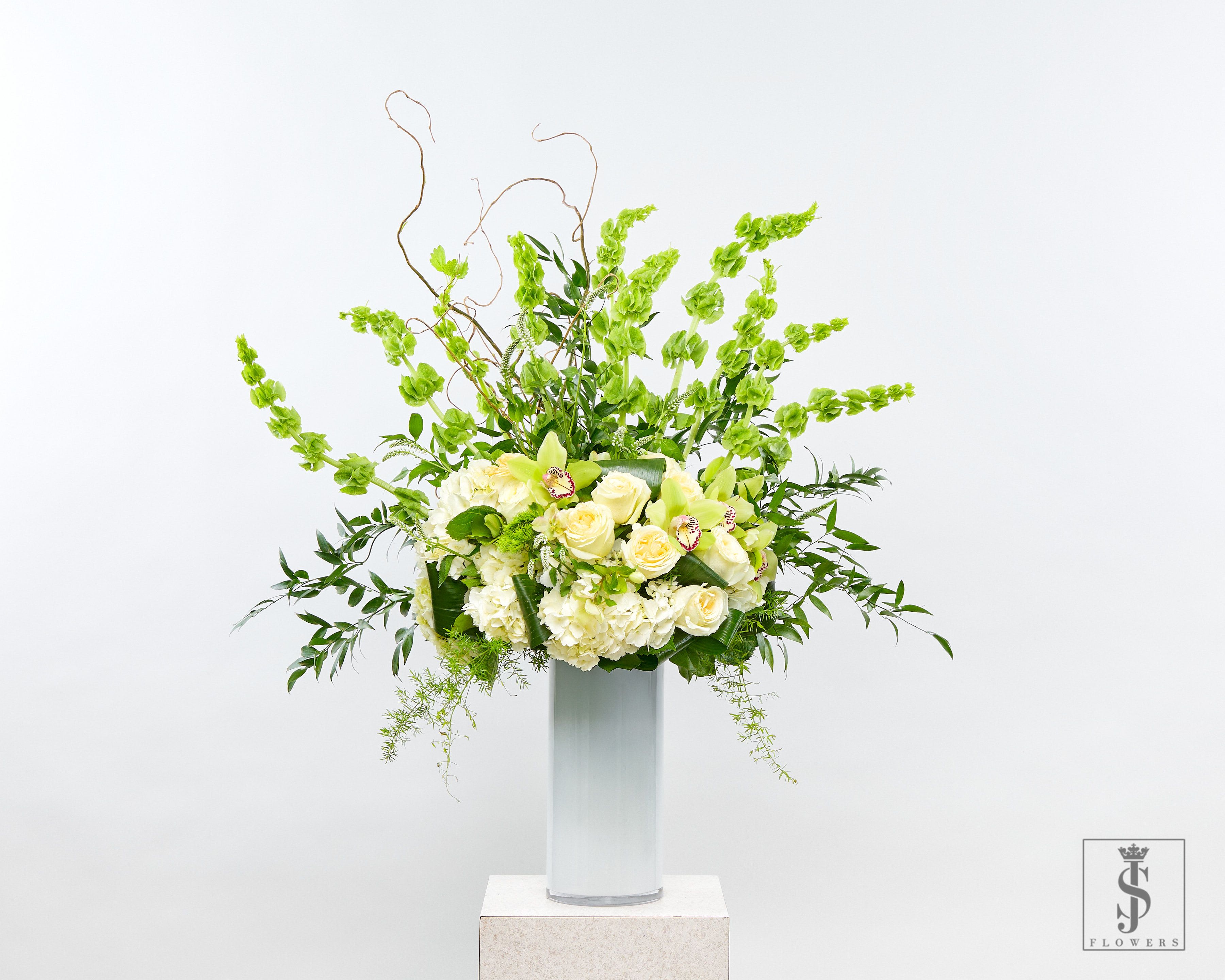 Tall white and green floral arrangement in a clear vase