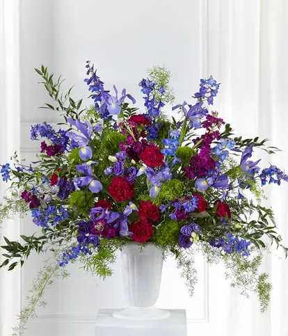 Large mixed floral arrangement in a white pedestal vase