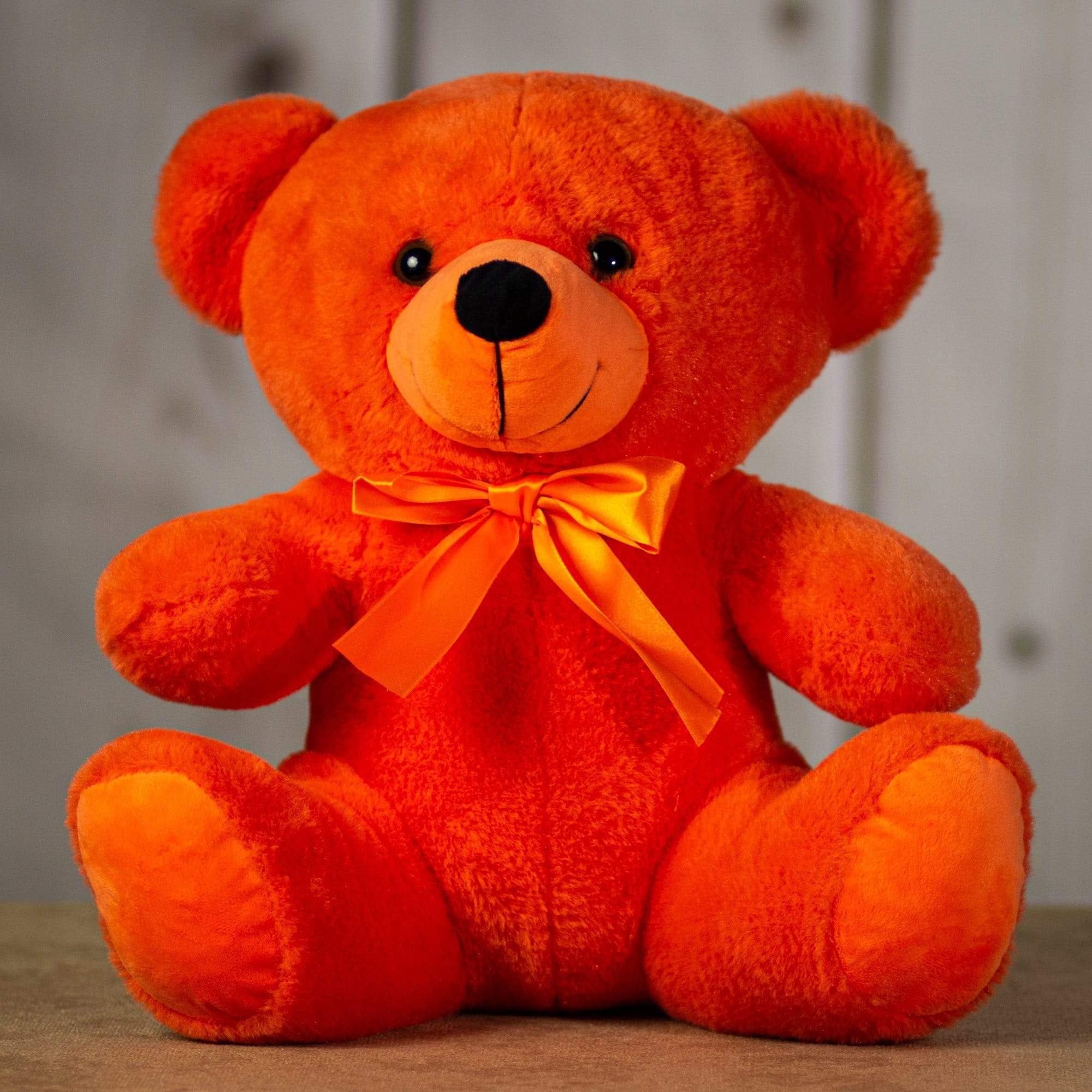 Orange plush teddy bear with a satin bow