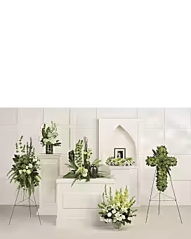 White floral funeral arrangements on stands and pedestals in a chapel setting