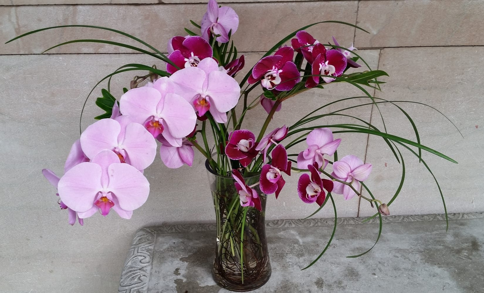 Pink and magenta orchids arranged in a clear glass vase