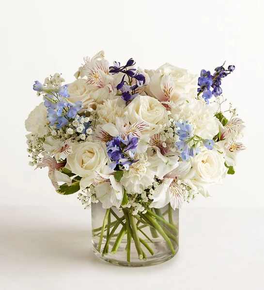 White and blue mixed bouquet in a clear glass vase