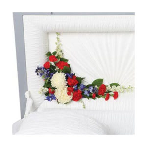 Floral casket spray with red, white, and blue flowers on a white casket