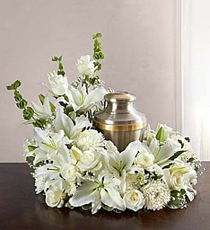 White floral funeral wreath around a brass urn