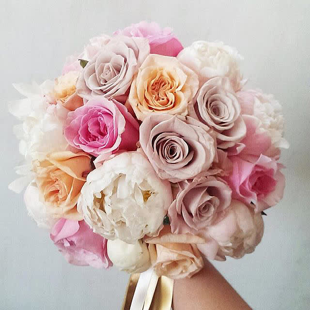 Round bouquet of pastel roses and peonies tied with ribbon