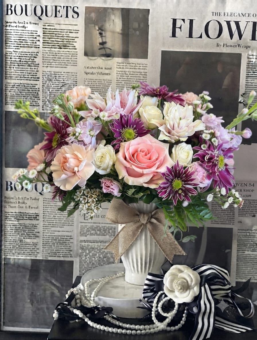 Pink and purple mixed bouquet in a white vase with a burlap bow