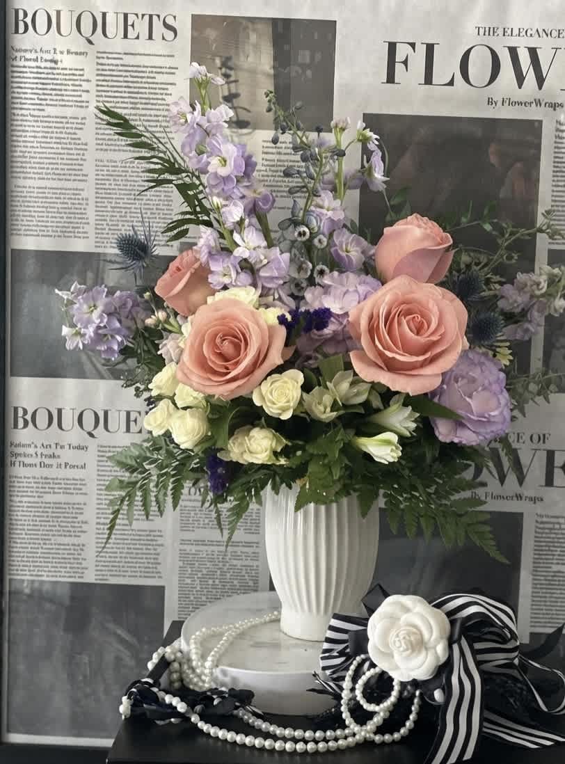 Pastel floral arrangement in a white vase with roses and lavender blooms