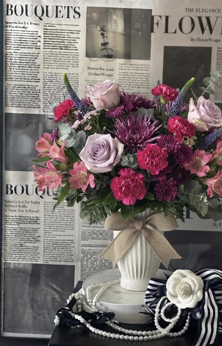 Bouquet of pink, lavender, and purple flowers in a white vase with a bow