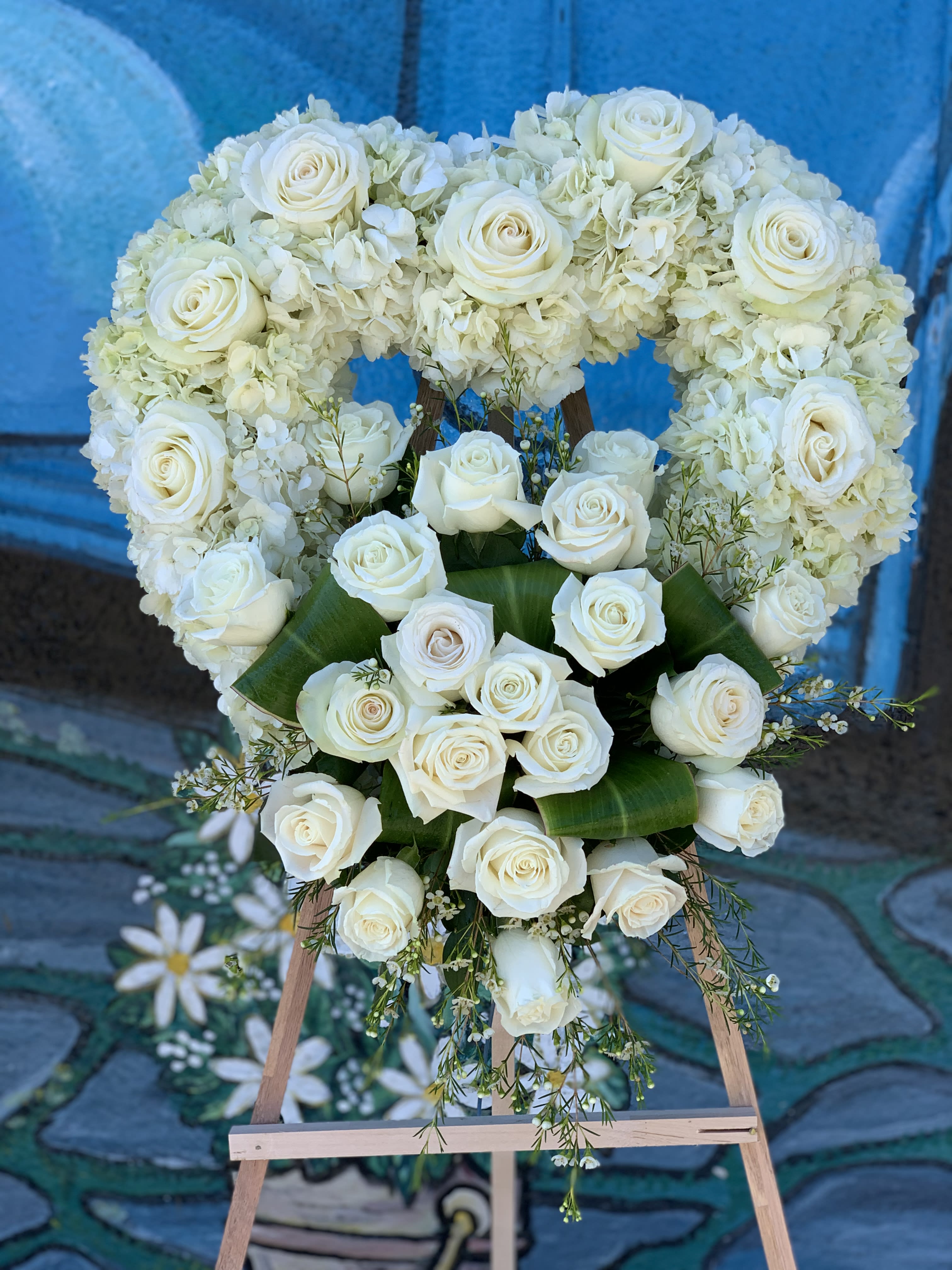 Heart-shaped white rose and hydrangea floral wreath on an easel
