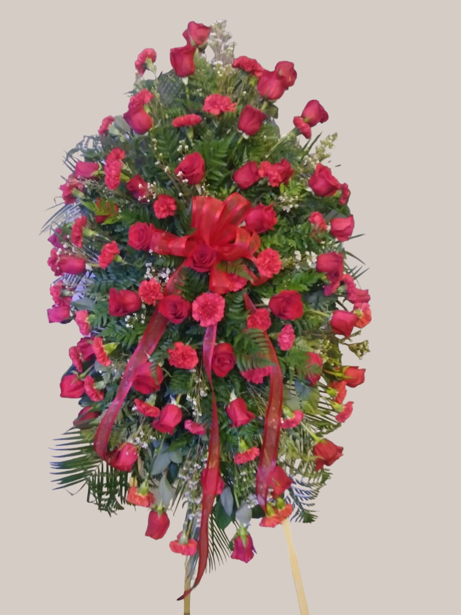 Standing floral spray of red roses and carnations with ribbon