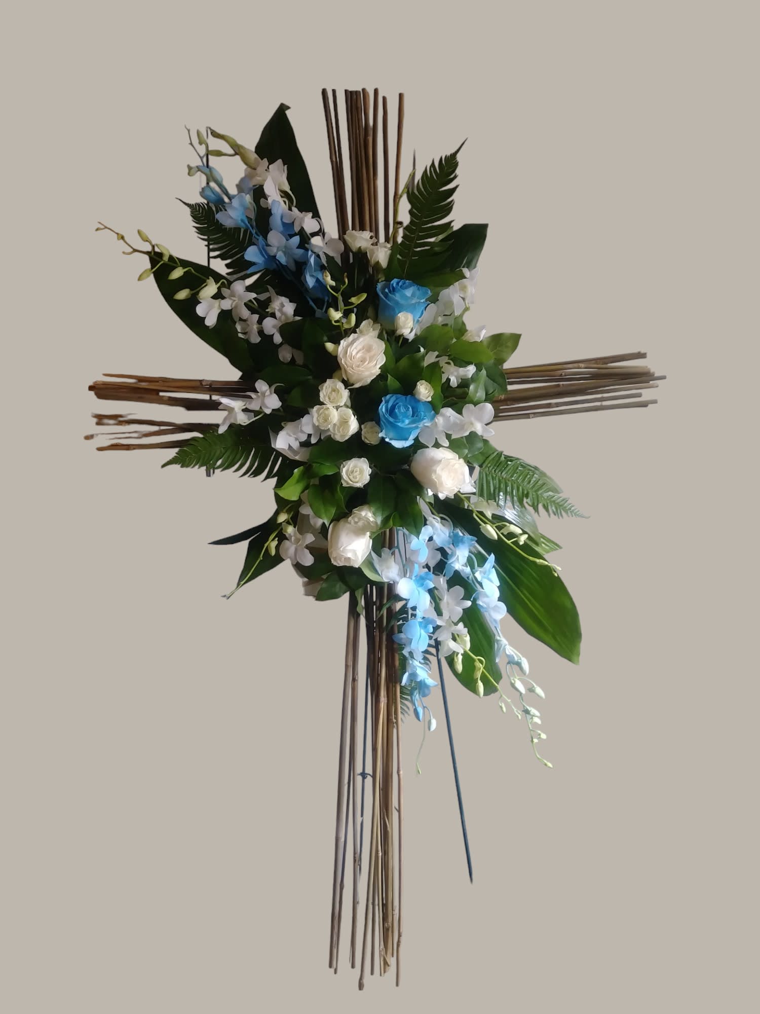 Cross-shaped floral arrangement with blue and white flowers on a wooden stand