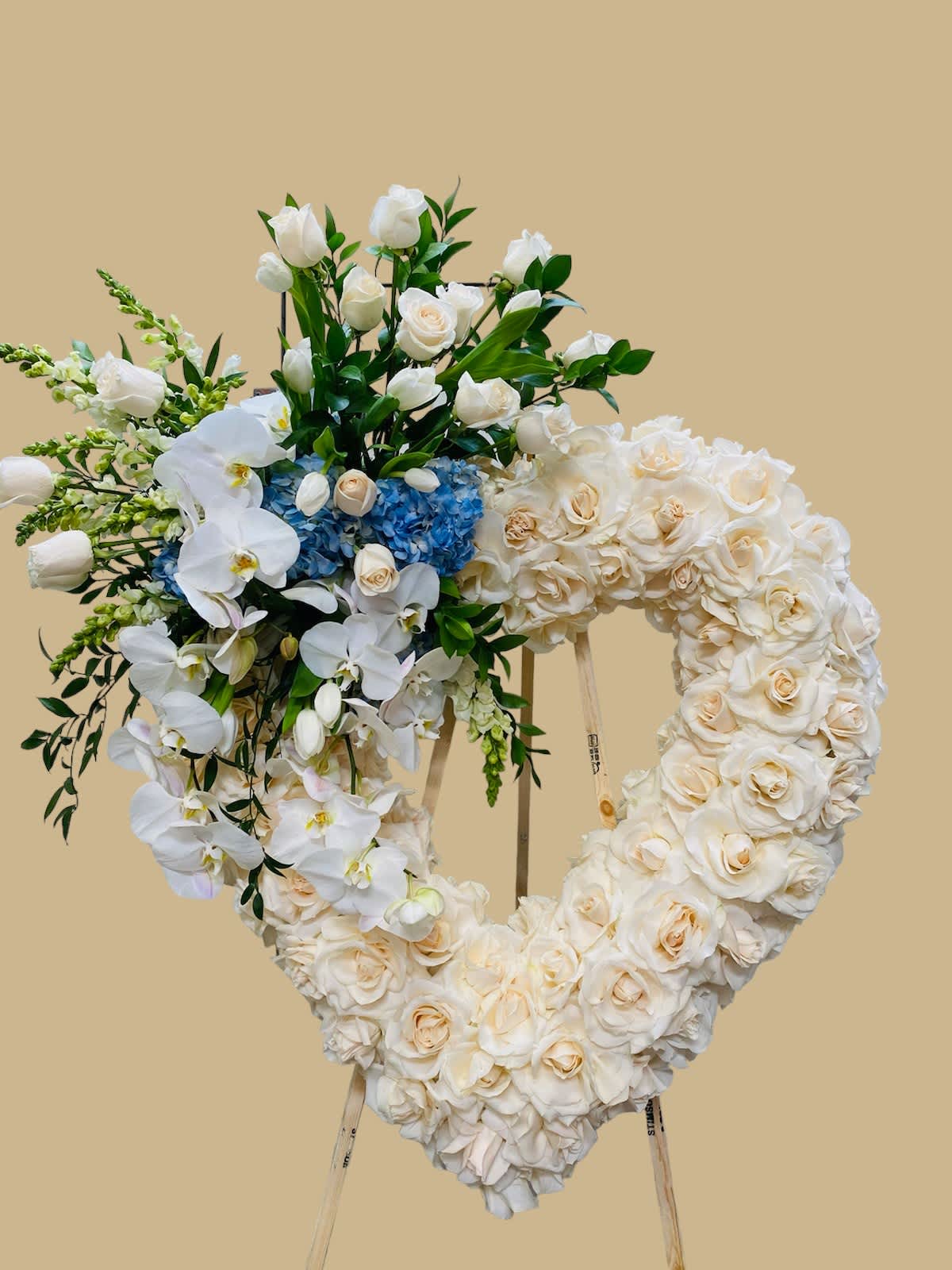 Heart-shaped floral wreath on an easel with white roses and orchids