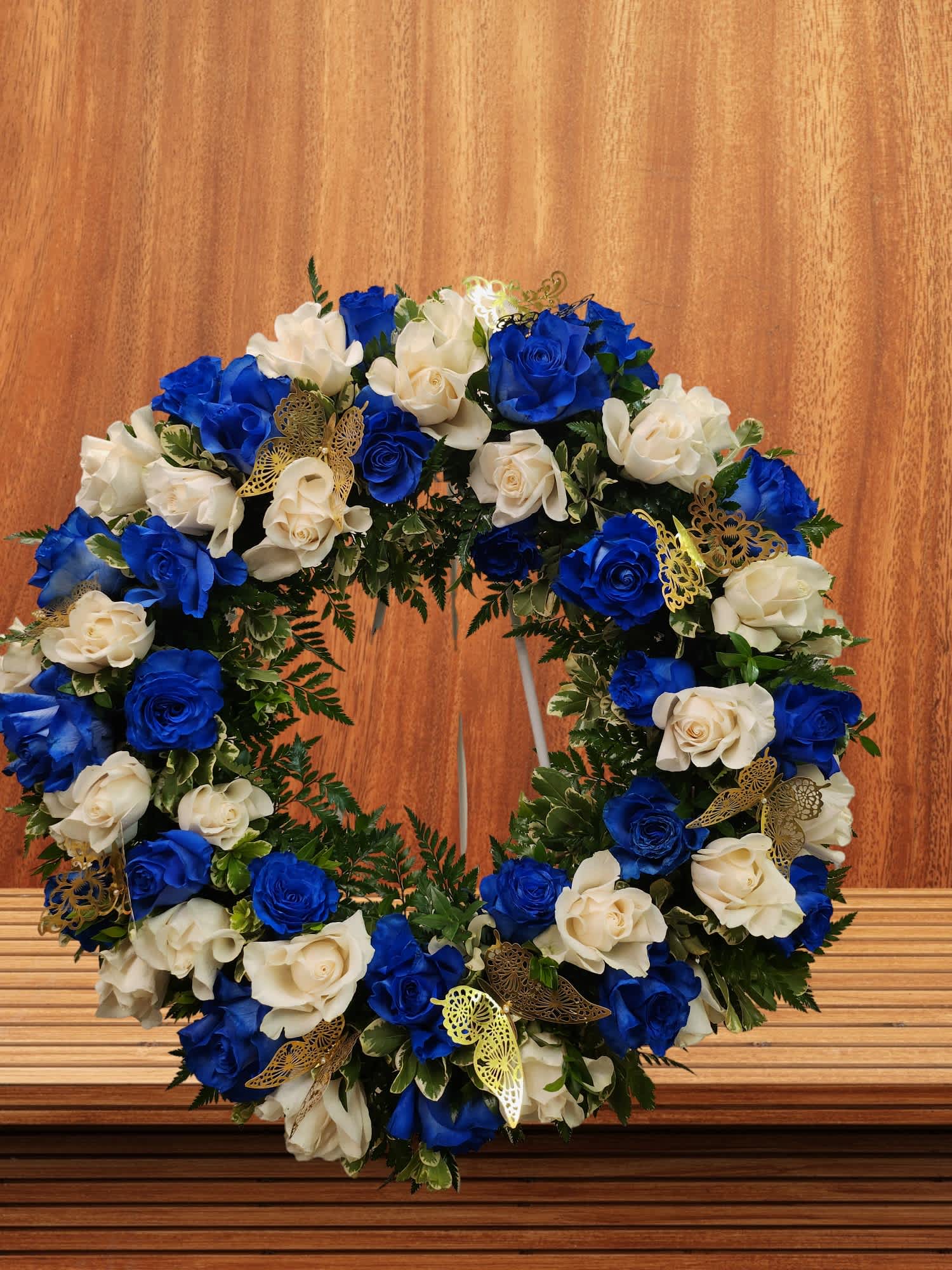 Circular wreath of blue and white roses with gold butterfly accents