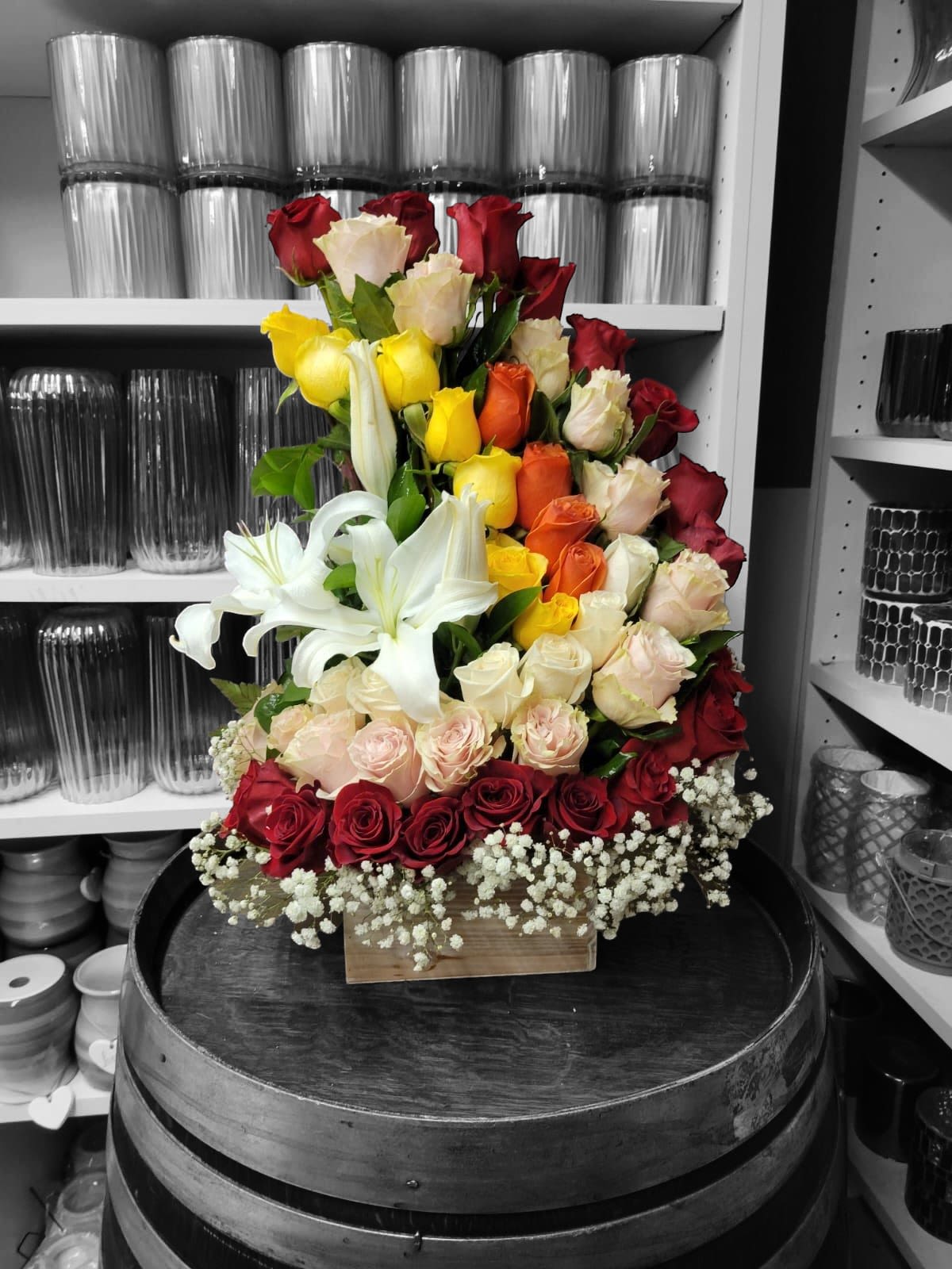 Tall bouquet of red, yellow, white, and peach roses with white lilies
