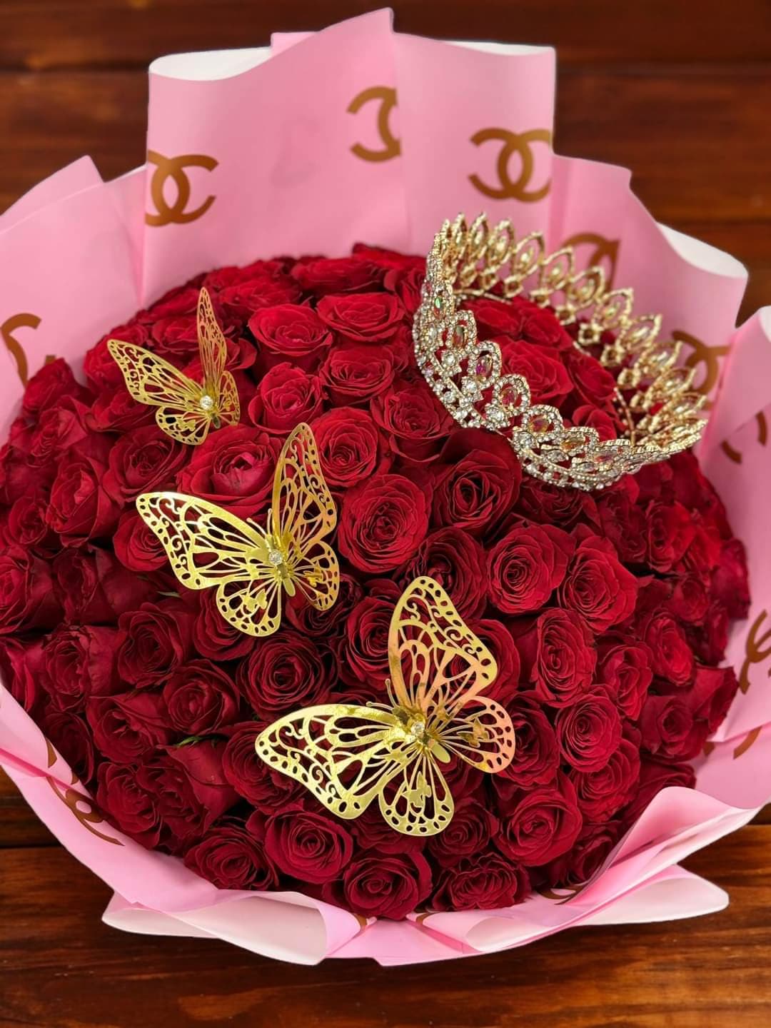 Bouquet of red roses wrapped in pink paper with gold butterfly accents