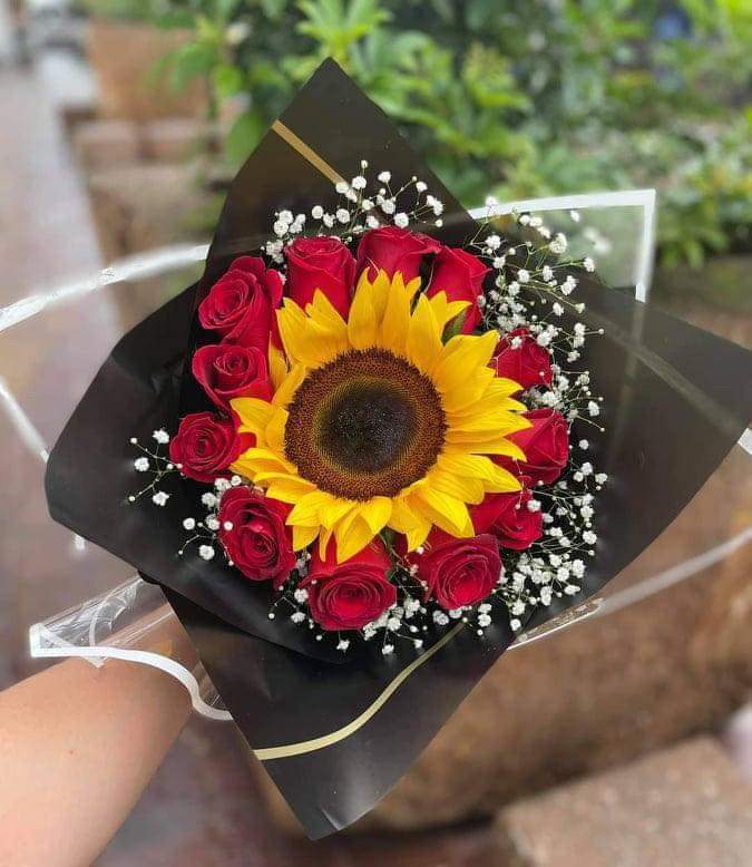 Bouquet of red roses with a sunflower and baby's breath in black wrap