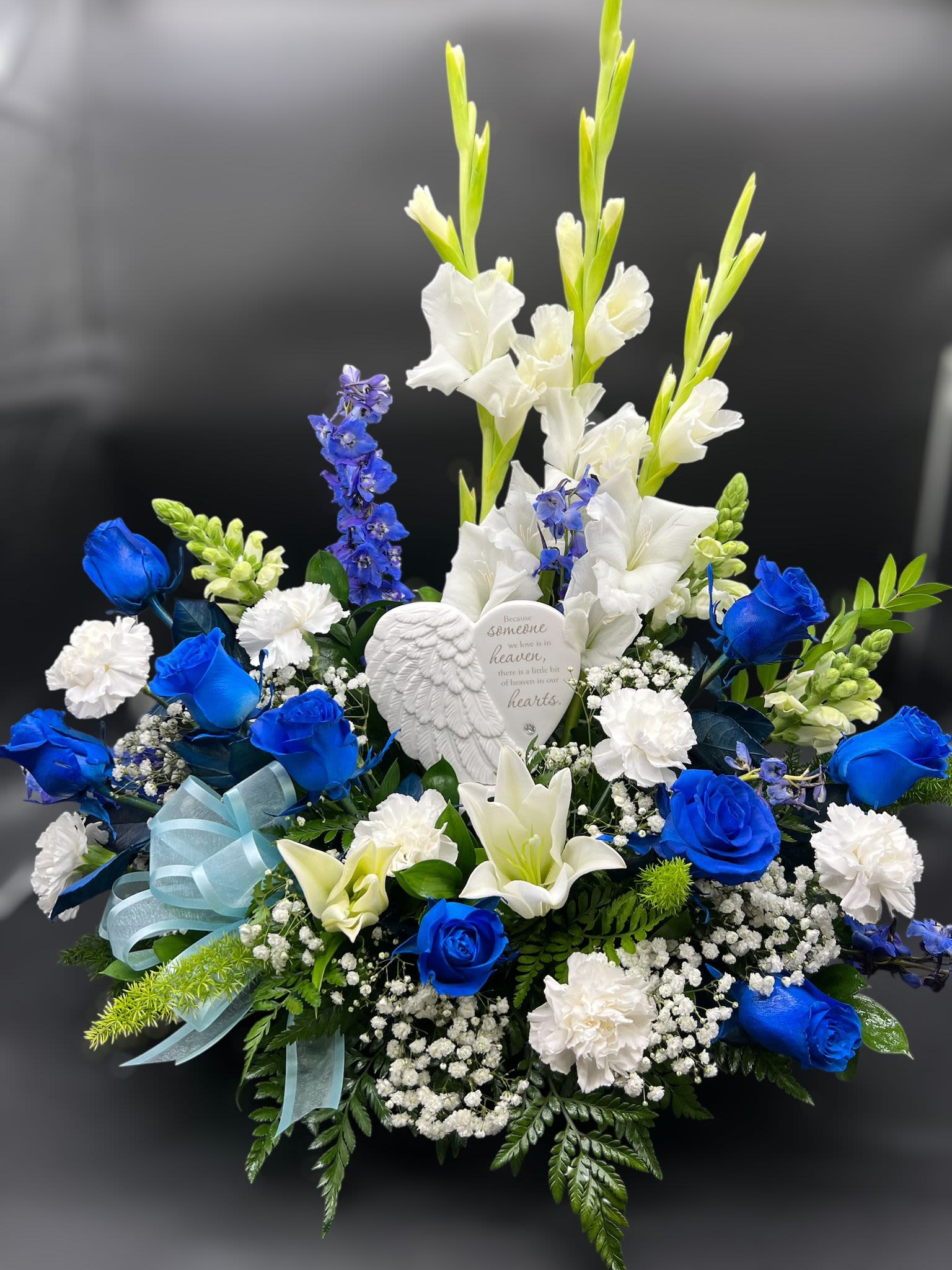 Blue and white floral sympathy arrangement with a memorial heart ornament
