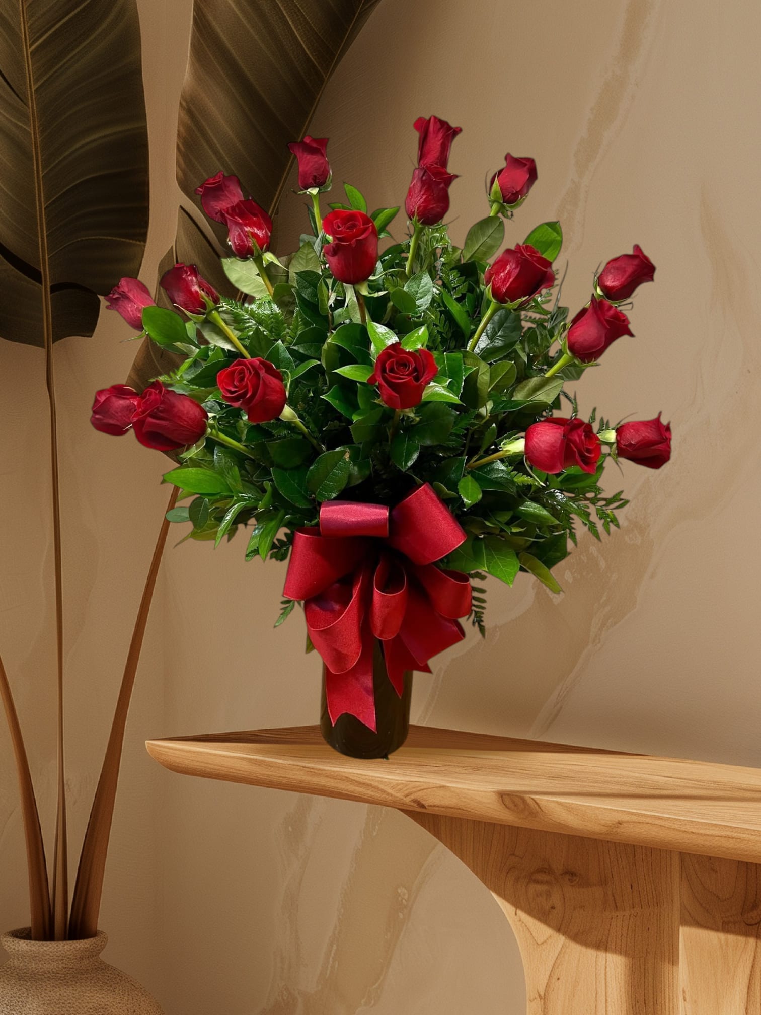 Red roses arranged in a black vase with a large red ribbon