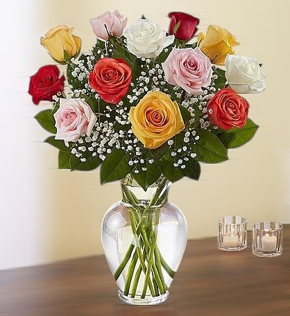 Colors of Love - A delightful bouquet of mixed-color roses, each bloom radiating its own unique charm, beautifully accented with delicate gypsophilia (baby's breath). Arranged in a classic clear glass vase, this vibrant and elegant display is perfect for celebrating any occasion or expressing heartfelt sentiments with timeless beauty.