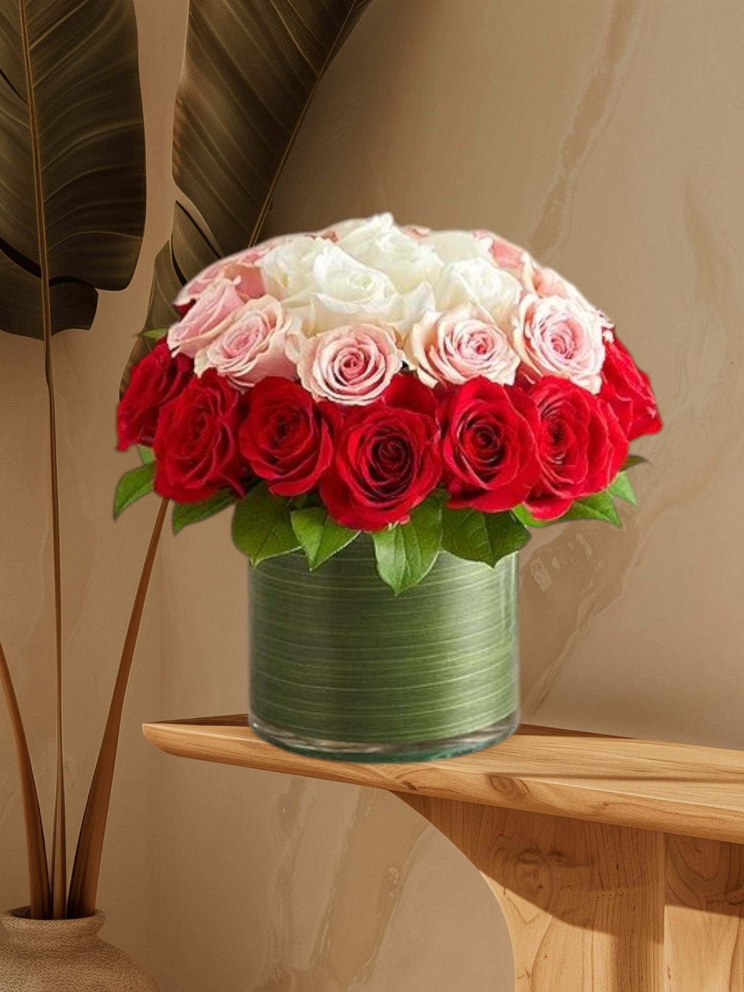 Red, pink, and white roses arranged in a glass vase