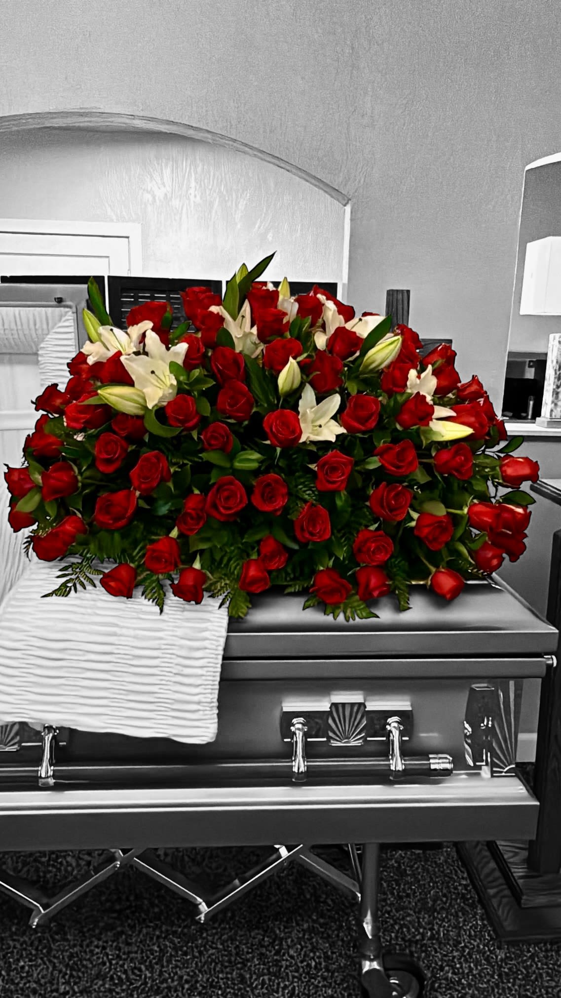 Red roses and white lilies arranged on a silver casket