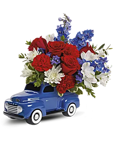 Blue toy truck filled with red, white, and blue flowers