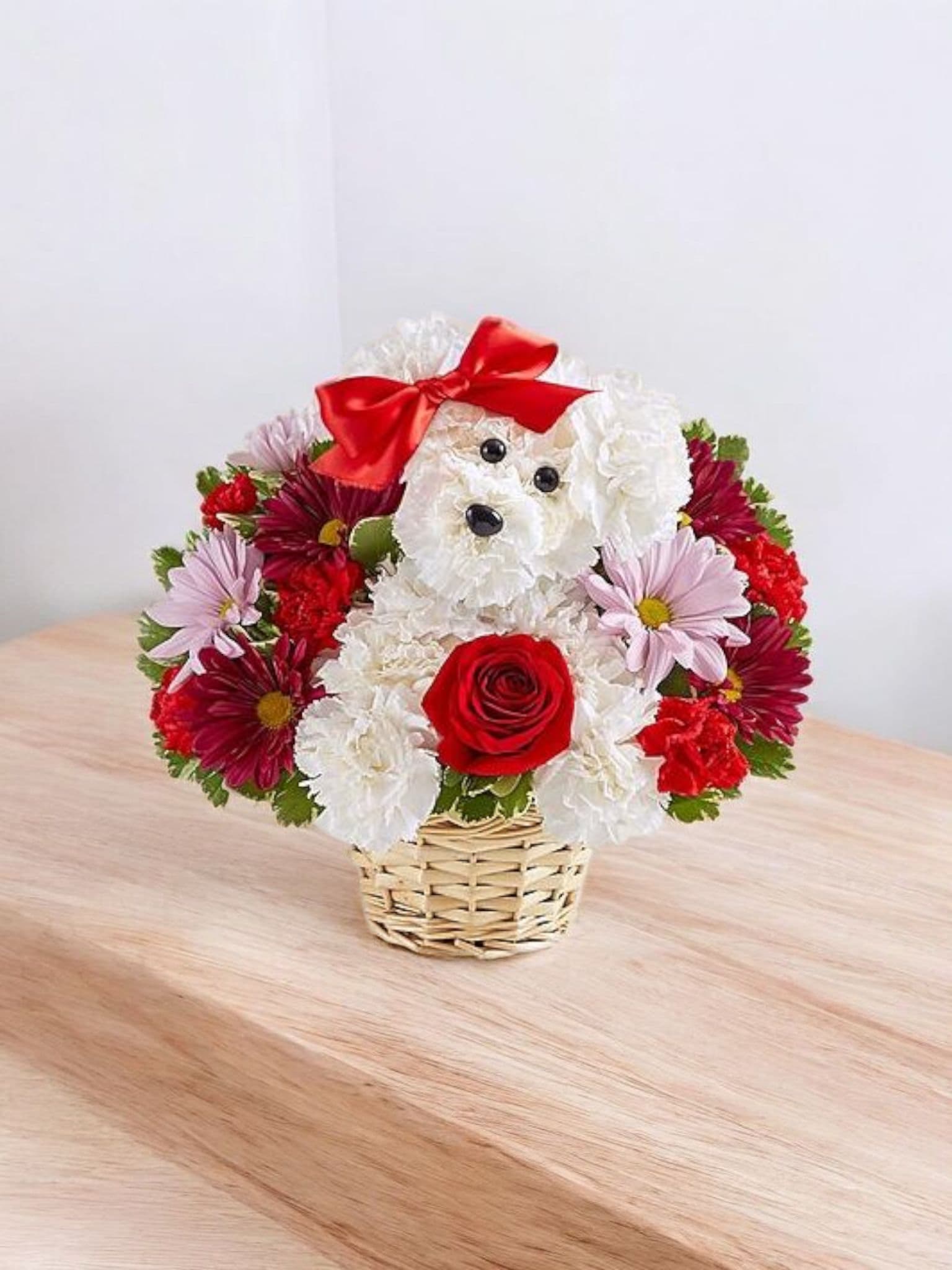 Flower arrangement shaped like a teddy bear with a red bow in a basket