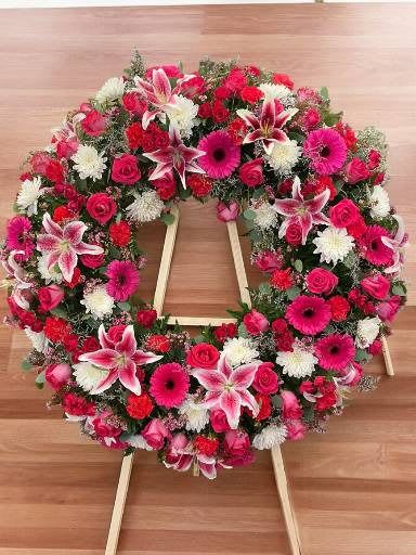 Heart-shaped floral wreath on a wooden easel with pink, red, and white blooms