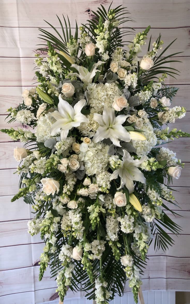Large white funeral spray with lilies, roses, and cascading blooms