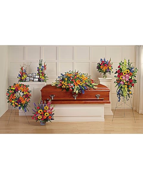 Colorful funeral casket spray with standing floral tributes
