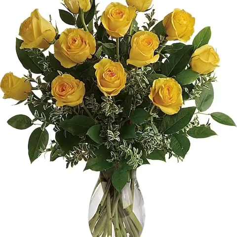 Yellow roses arranged in a clear glass vase with greenery