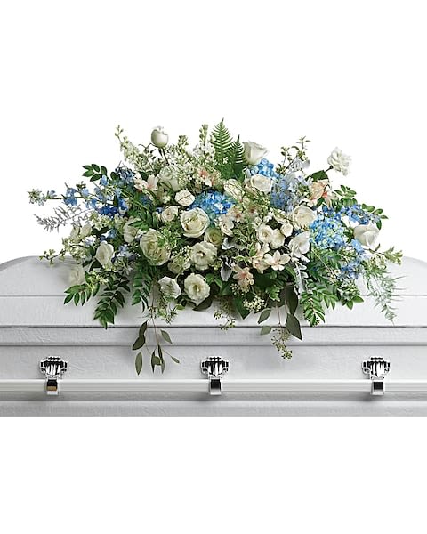 White and blue floral casket spray on a white coffin
