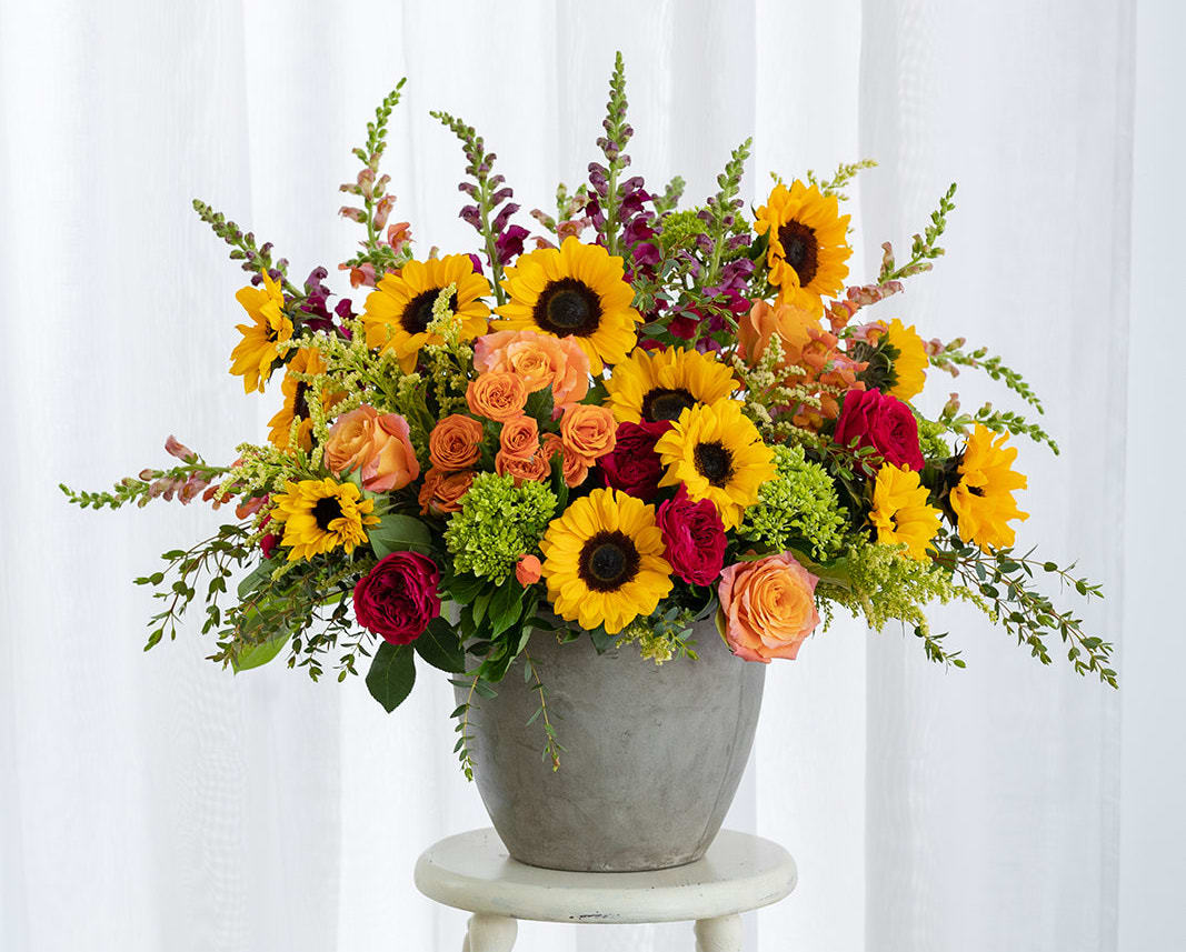 Mixed bouquet of sunflowers and roses in a gray vase