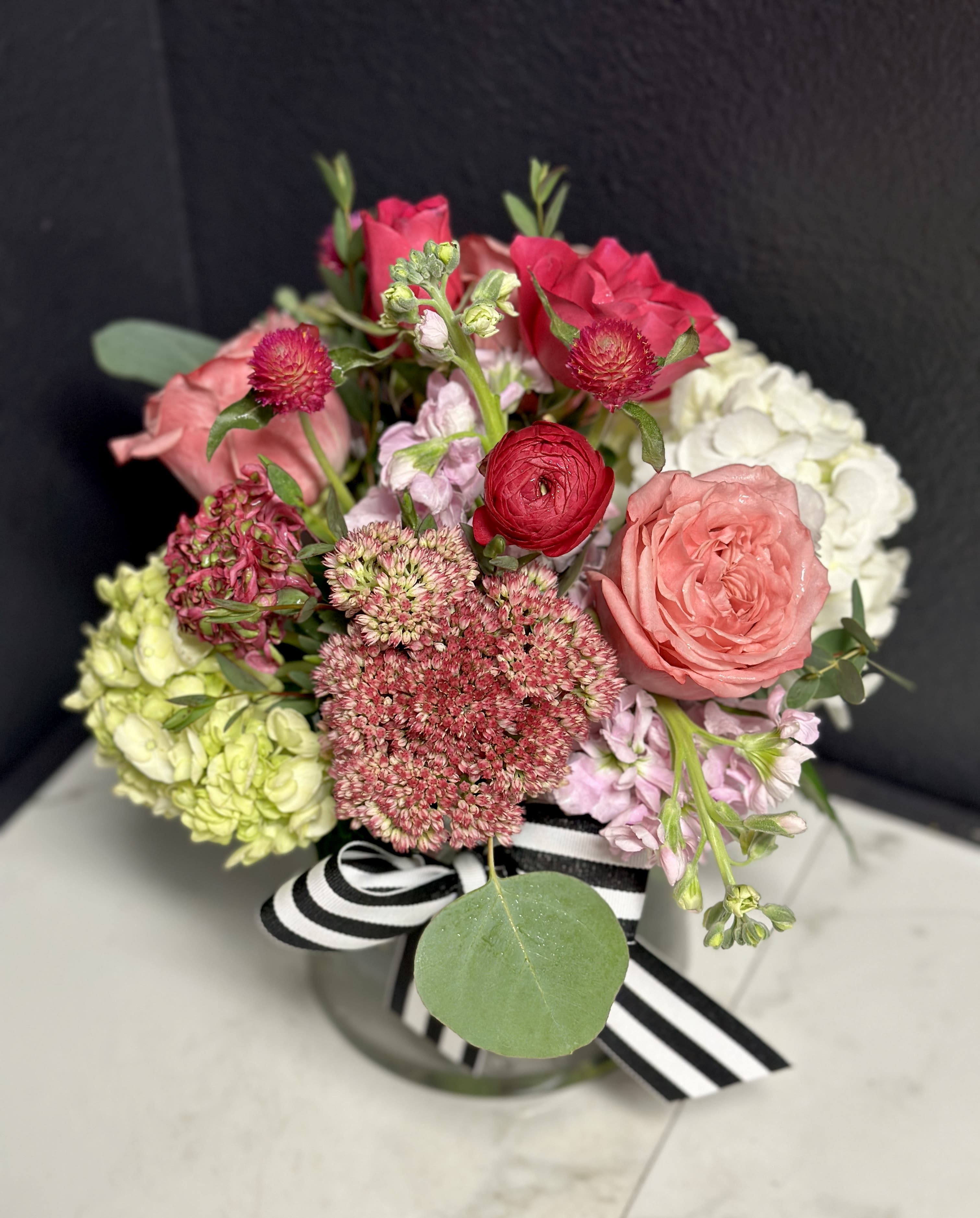 Mixed pink and white bouquet in a glass vase with a striped ribbon