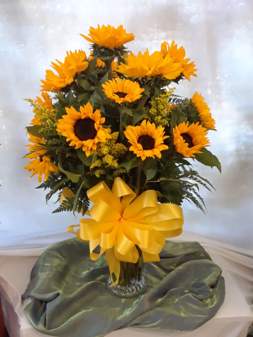 Sunflower arrangement in a glass vase with a yellow bow