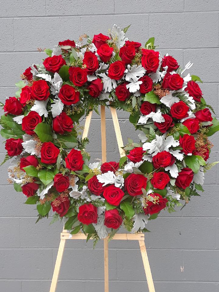 Red rose wreath on a wooden easel with silver foliage accents
