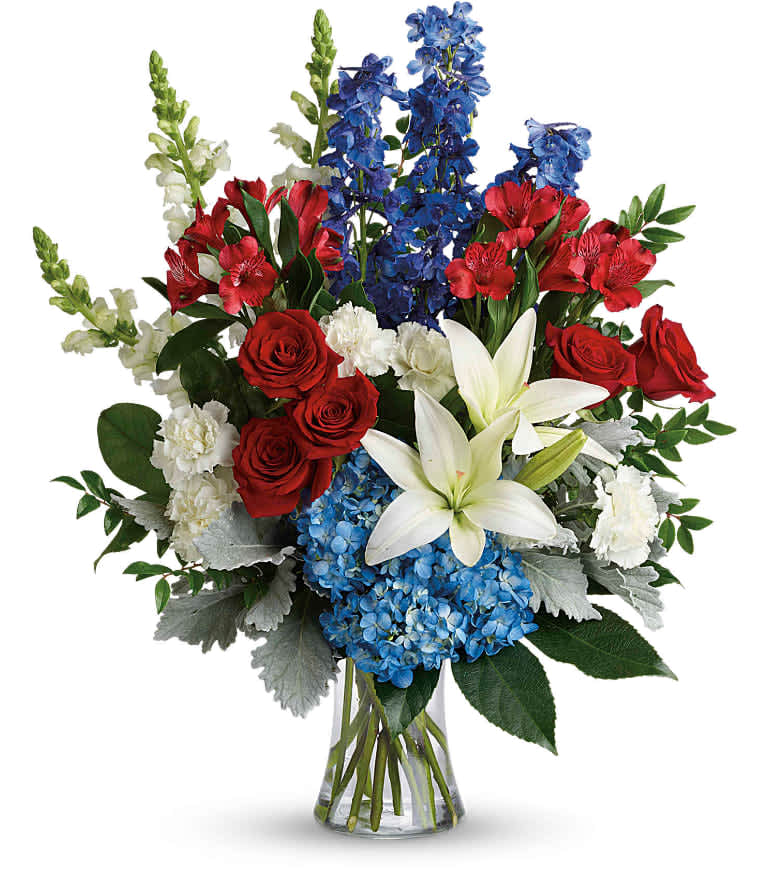Colorful Tribute Bouquet - Perfectly patriotic with its red, white and blue blooms, this bold bouquet of hydrangea, lilies and roses is a versatile tribute on any occasion. This bouquet features blue hydrangea, red roses, white asiatic lilies, red alstroemeria, white carnations, blue delphinium, white snapdragons, huckleberry, dusty miller, aralia leaf and lemon leaf. Delivered in a gathering vase. Approximately 22" W x 26" H