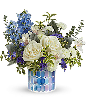 Teleflora's Spreading Light Bouquet - Spreading light, this blue sky-inspired bouquet of cloudy white roses looks heavenly in a keepsake mosaic vase with iridescent finish. This arrangement includes crème roses, white alstroemeria, light blue delphinium, white button spray chrysanthemums, purple sinuata statice, dusty miller, spiral eucalyptus and pitta negra. Delivered in Teleflora's Blue Beauty Mosaic Vase. Orientation: All-Around