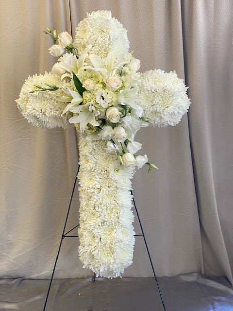 White floral cross arrangement on a stand